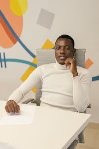 Elegantly dressed man posing confidently in a modern office setting.